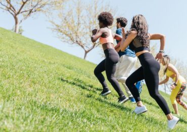Several people running up a hill during their workout, as part of their gym's rewards program challenge.