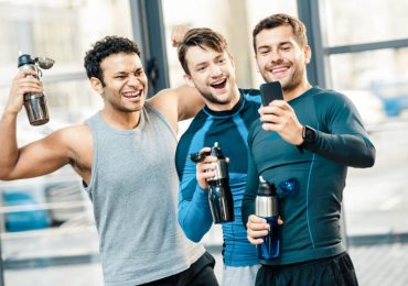 gym rewards program, three happy friends looking at phone