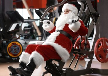 Santa working hard on a bench press machine, staying motivated in his holiday workout routine.