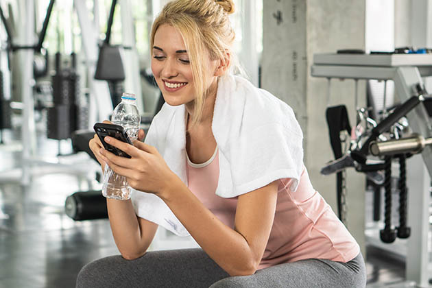 staff loyalty, woman using phone in gym