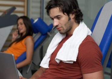 A gym owner building his online fitness store on his laptop with the help of WellnessLiving.