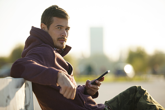 martial arts studio, man In hoodie holding mobile phone texting outdoors