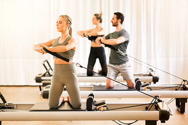 Pilates studio, group of people doing pilates torsion rotation exercises