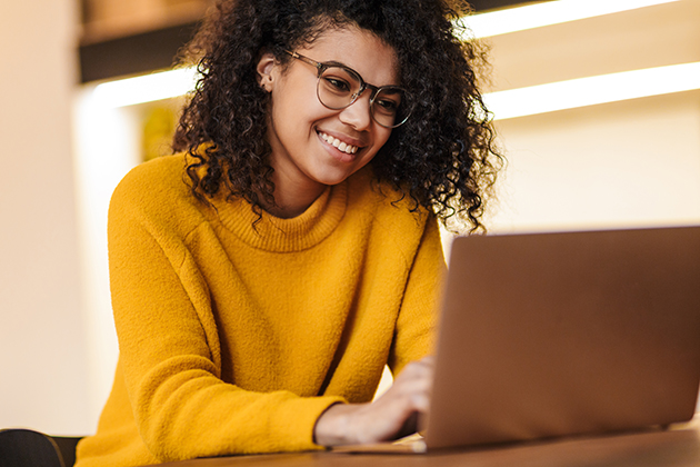 marketing to members, cheerful African American woman in eyeglasses using laptop