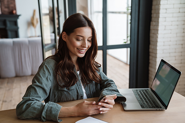 marketing strategies, beautiful smiling woman using cellphone while working with laptop