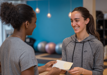 Yoga instructor hands birthday card to student