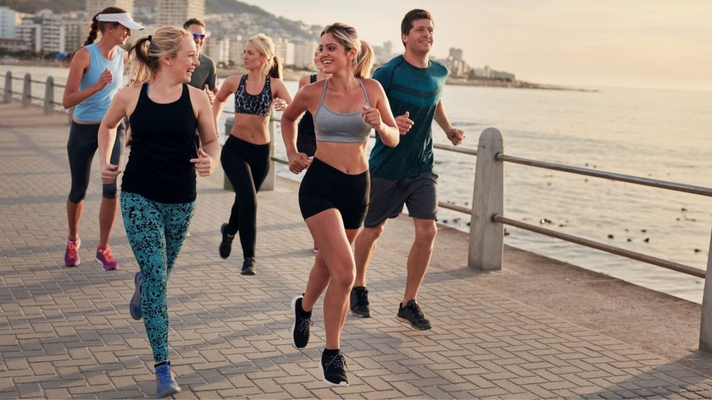 A running club of diverse people out for a run before returning to their fitness center.