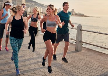 A running club of diverse people out for a run before returning to their fitness center.