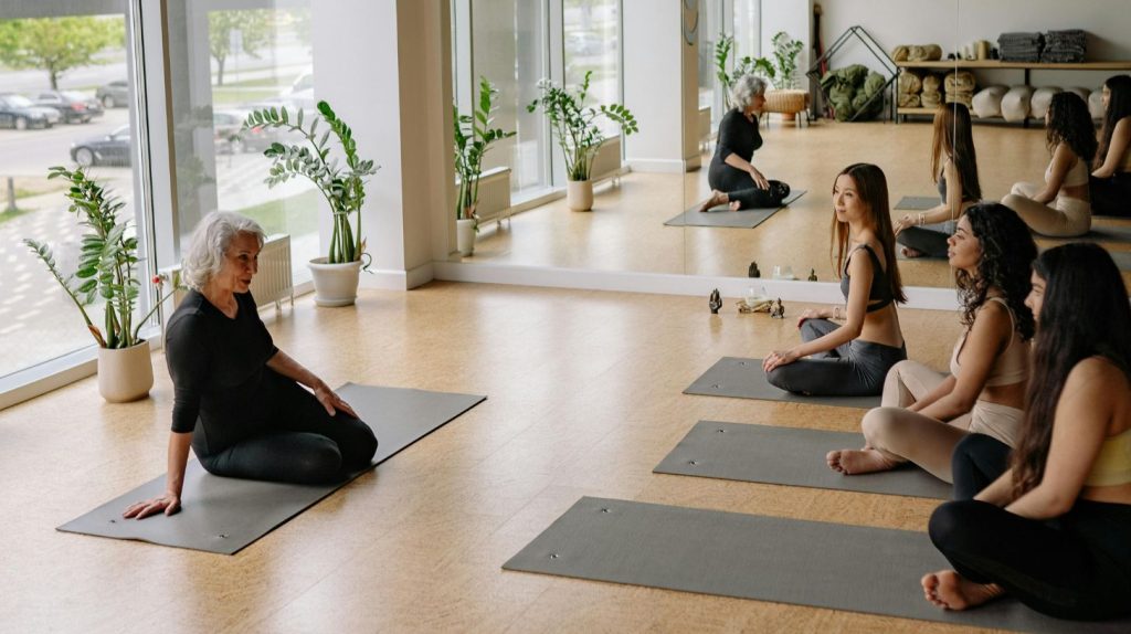 A yoga teacher talks with her class about the new booking software they'll be using.