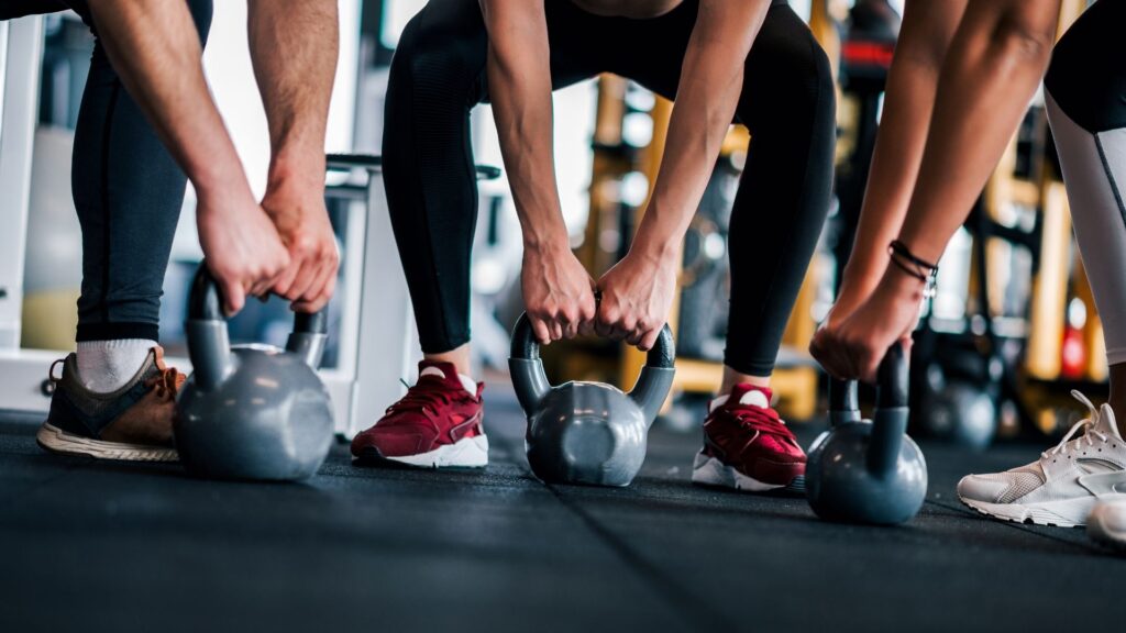 A group of people squatting down to grab their weight during a CrossFit class.