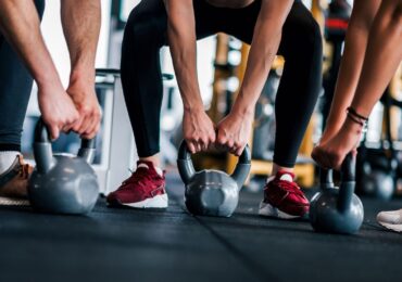 A group of people squatting down to grab their weight during a CrossFit class.