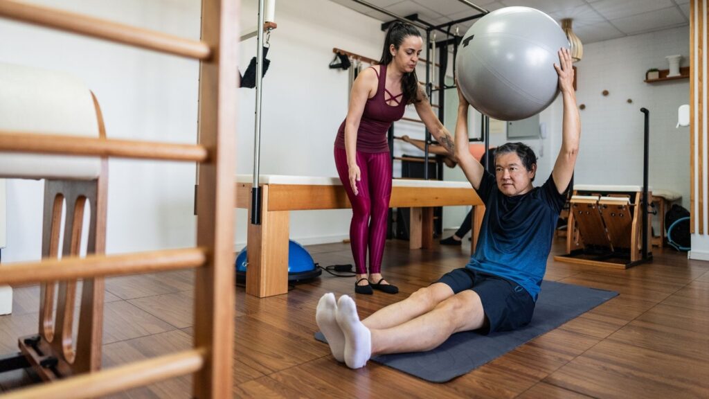 A Pilates studio owner helping a new client through their workout.