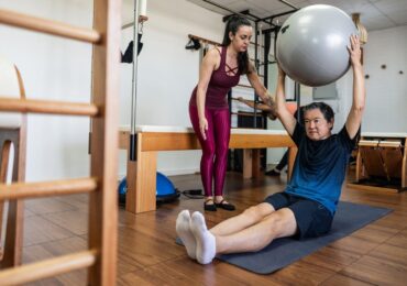 A Pilates studio owner helping a new client through their workout.