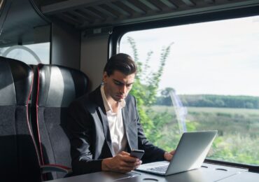 A small business owner checks his email and messages while on a train.