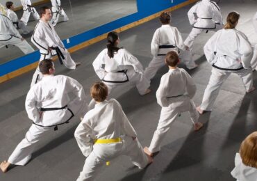 A busy martial arts school begins their class with stretching routines.
