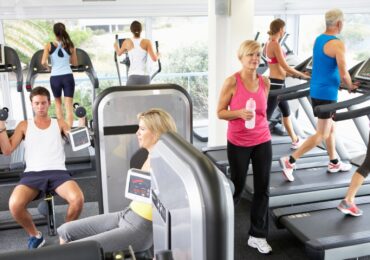 A busy fitness studio, packed with people exercising.