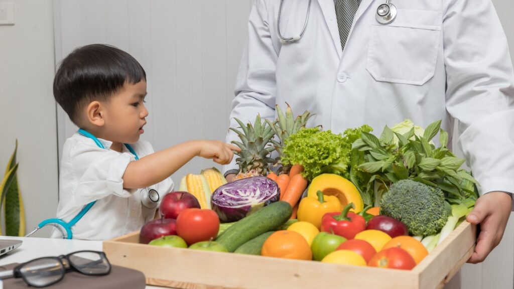 A nutritionist showing a child a variety of colorful fruits and vegetables.