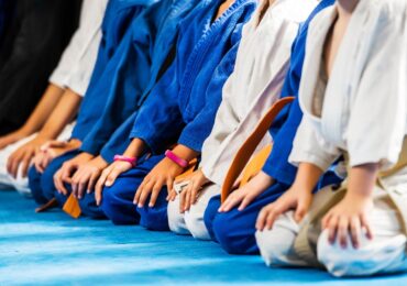Students at the D'Souza Martial Arts Academy, kneeling on the mat before a class.
