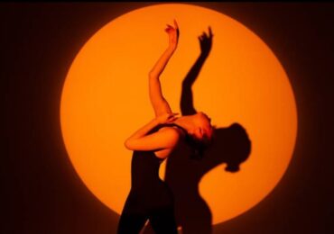 A dancer at Kinesi Dance Complex, posing in the spotlight.