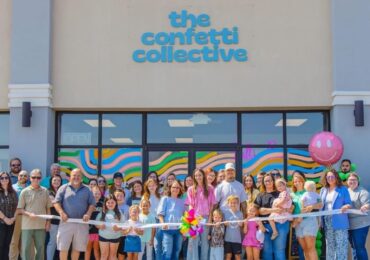A large group of people gathering in front of The Confetti Collective at their grand opening.