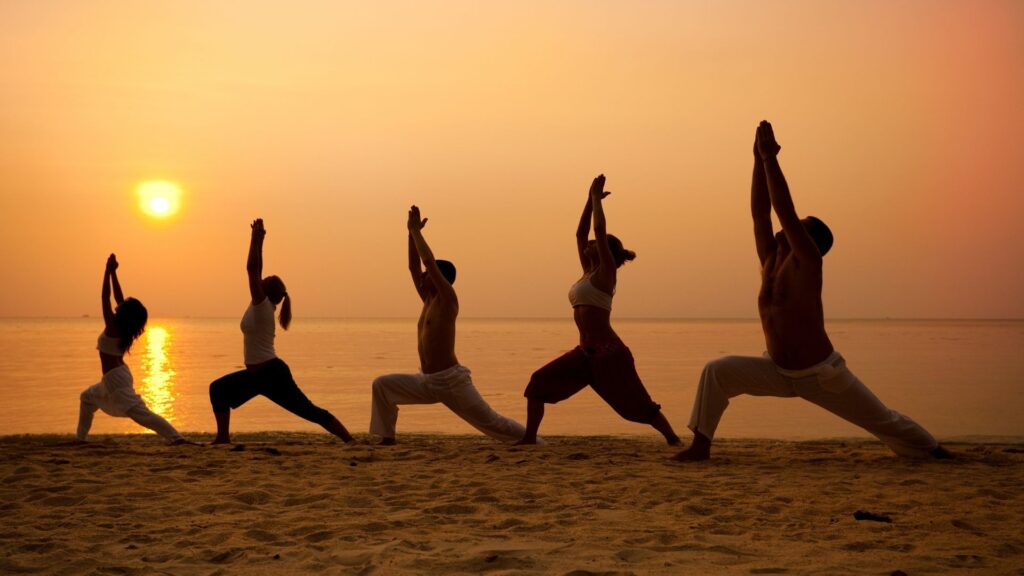 A group of people from the Know Yoga center, doing yoga on the beach.
