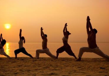 A group of people from the Know Yoga center, doing yoga on the beach.