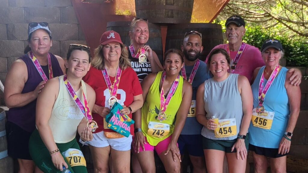 A group of runners from Bug Out Training, posing together with medals from a marathon.