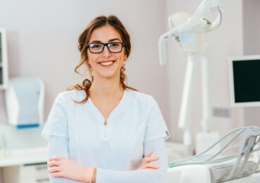 The owner of a dental practice, stands proudly in front of her new equipment.