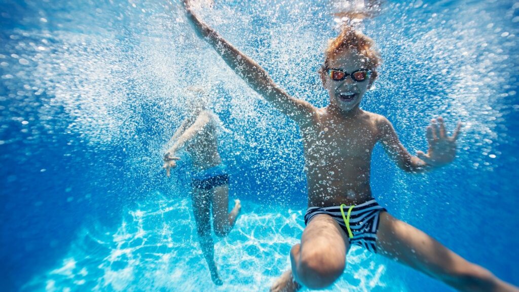A child diving into a pool with the Raynboe Swan swim school.