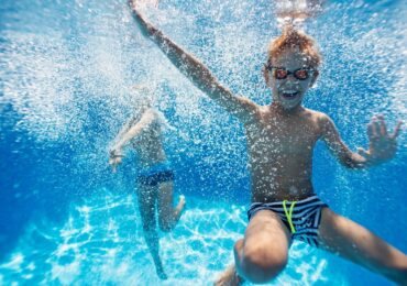 A child diving into a pool with the Raynboe Swan swim school.