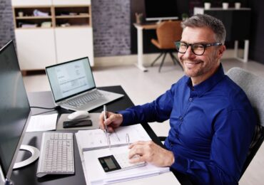 A small business owner, doing his accounting at his desk.