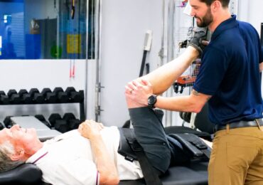 The owner of Move Mint Condition, helping a senior client stretch his legs.