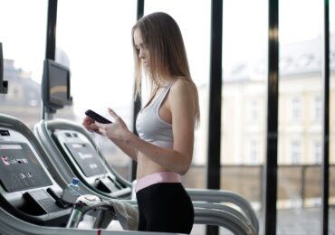 A woman receiving a text message promotion while on the treadmill at her gym.