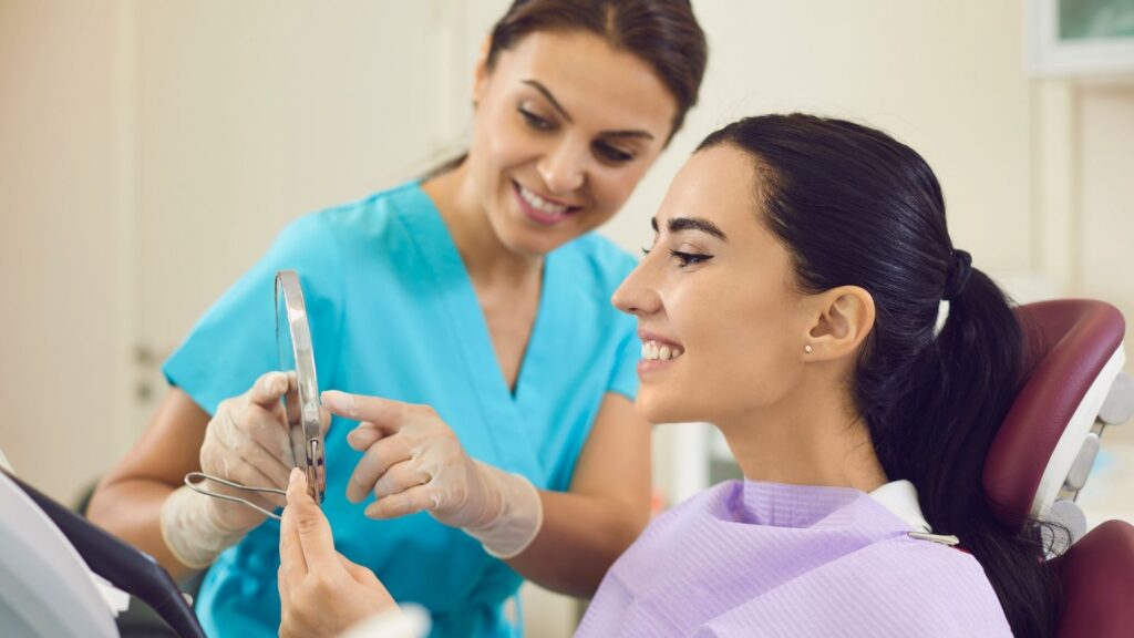 A dentist shows a client who booked with the AI dental receptionist CAASI, her new smile.