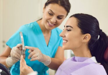A dentist shows a client who booked with the AI dental receptionist CAASI, her new smile.