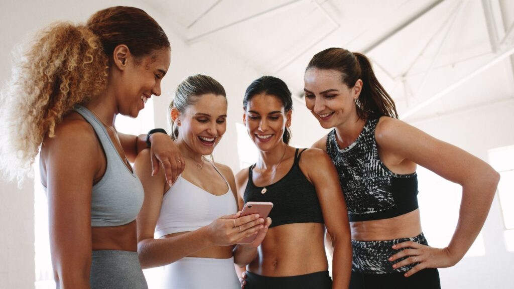 A group of friends booking their next fitness class with the help of WellnessLiving's software.