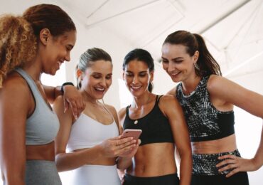 A group of friends booking their next fitness class with the help of WellnessLiving's software.