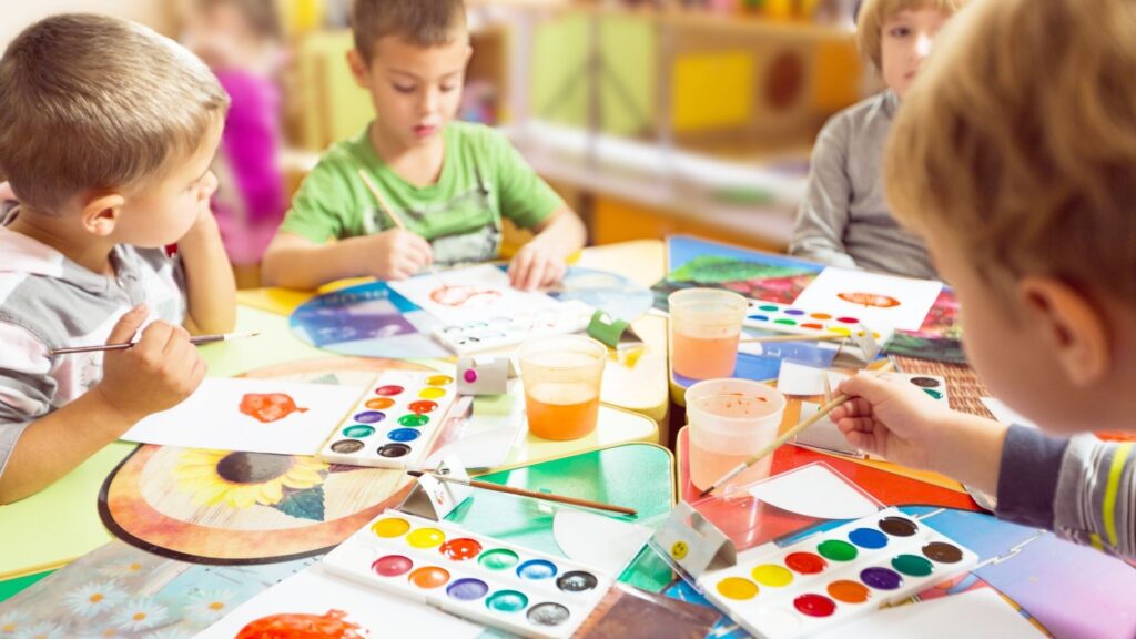 A group of young children at a play cafe, using watercolor paints together.