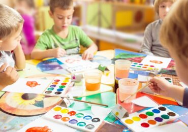 A group of young children at a play cafe, using watercolor paints together.