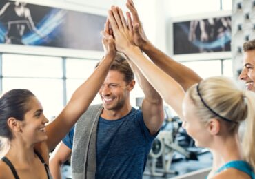 An excited group of gym clients, sharing a group high five after their class.