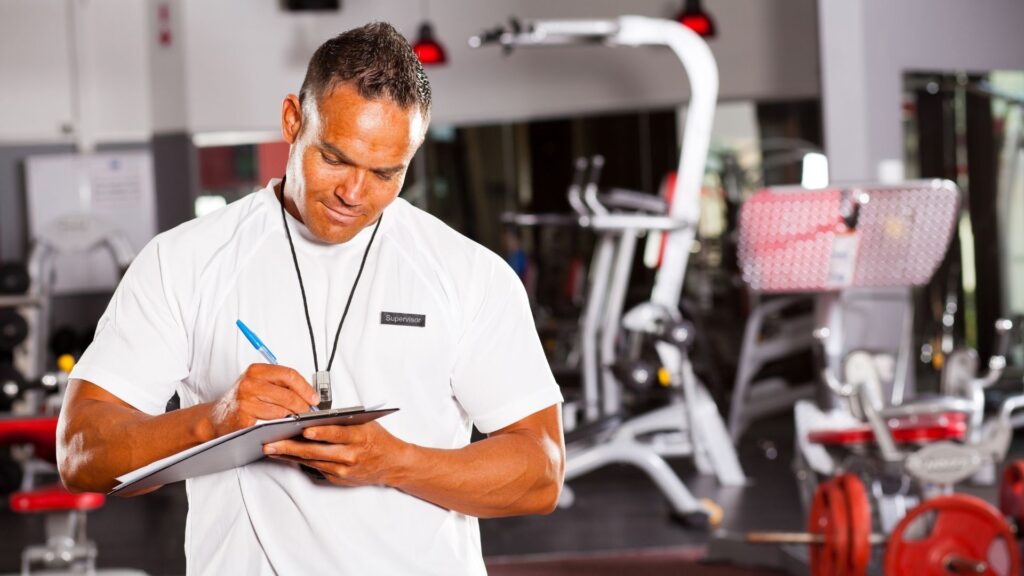 A gym owner taking down manual notes on class attendance because he doesn't have a gym analytics software system.