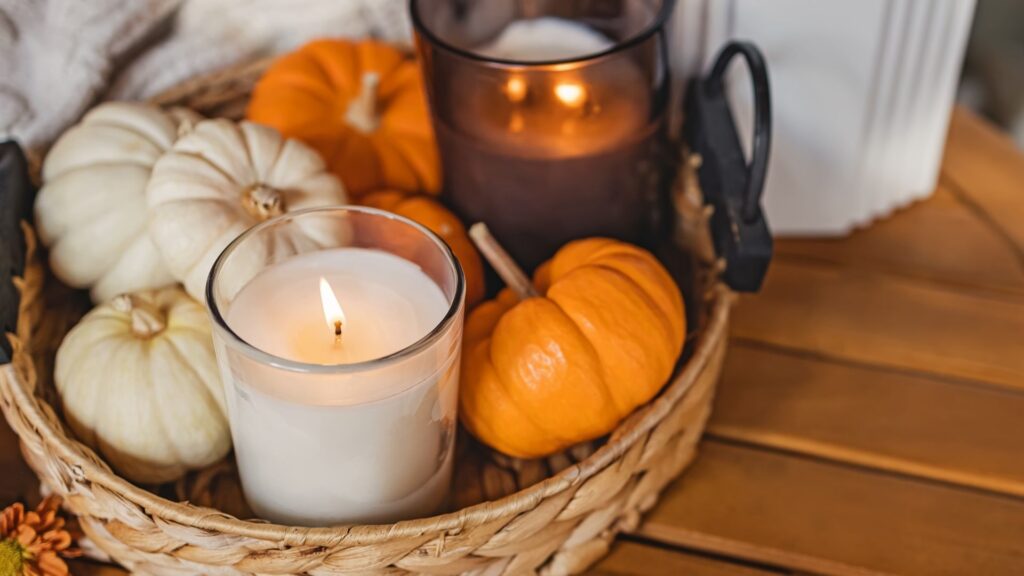 A basket of small pumpkins and a festive fall candle.