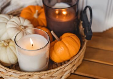 A basket of small pumpkins and a festive fall candle.