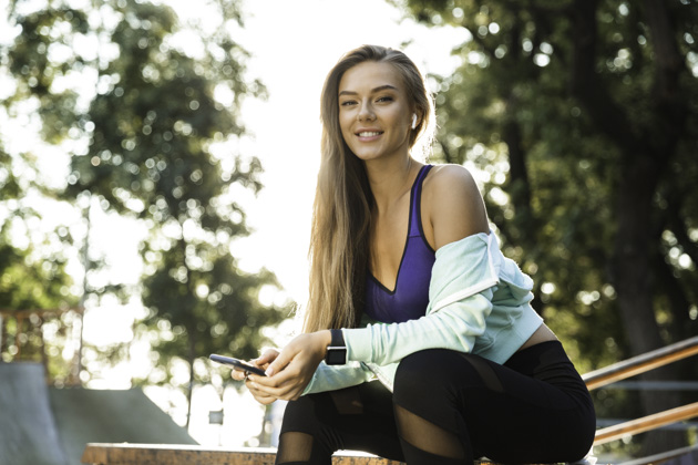 apps for dance studios, woman checking her phone in the park