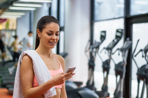 gym software, woman on phone in gym